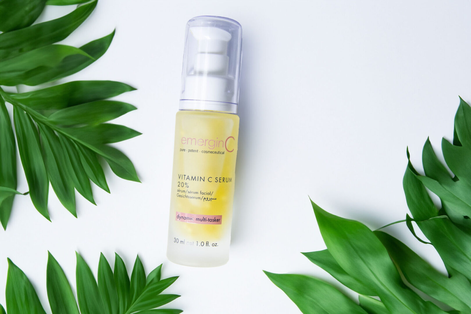 20% Vitamin C Serum A bottle of serum sitting on top of some green leaves.