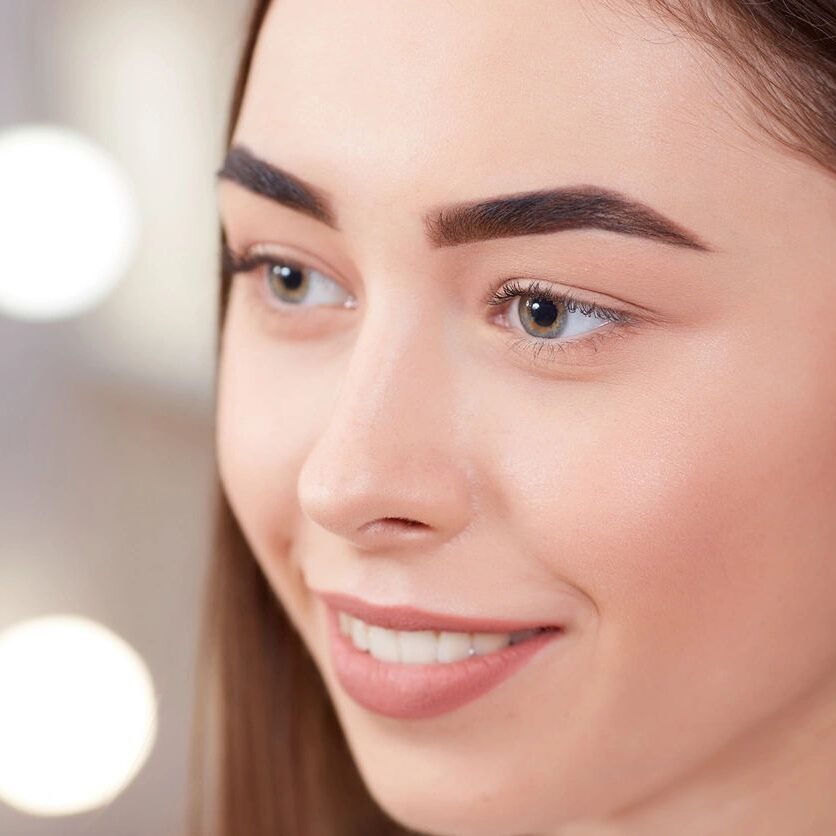 A woman with brown hair and blue eyes smiling.