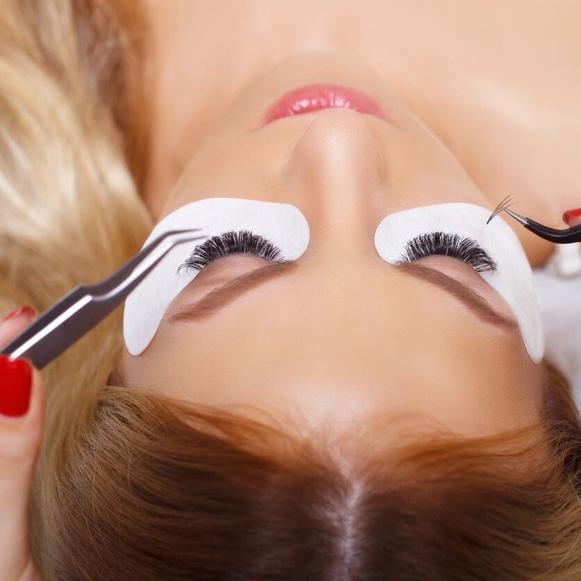 A woman is getting her eyelashes cut off.