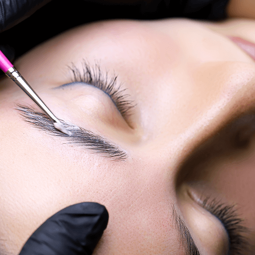 A woman getting her eyebrows threaded with a needle.
